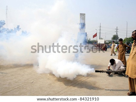 PESHAWAR, PAKISTAN - SEPT 08: Health workers busy in anti-Dengue spray at a road during fumigation campaign in Peshawar on Thursday, September 08, 2011.
