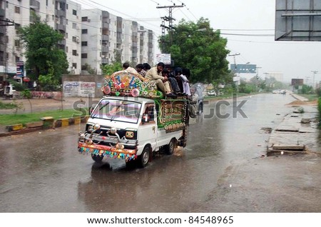 HYDERABAD - SEPT 12: Passengers travel on an overloaded passenger vehicle during downpour of Monsoon season in Hyderabad on September 12, 2011.