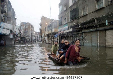 KARACHI, PAKISTAN - SEPTEMBER 13: A rain affected family travels on a push-cart at a flooded area at Burns road due to heavy downpour of Monsoon Season in Karachi September 13, 2011.