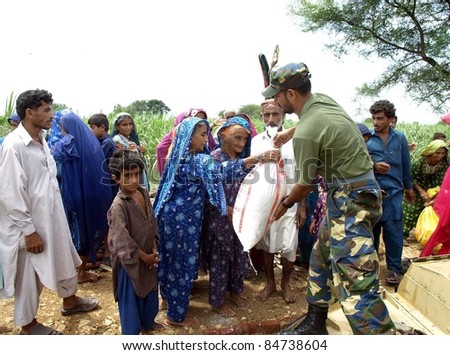 KARACHI, PAKISTAN - SEPT. 15: Navy soldiers distribute ration among flood affected people at a flood hit area of Sindh province in Karachi, Pakistan on September 15, 2011.
