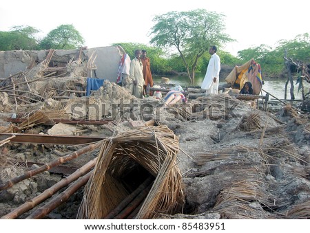KUNRI, PAKISTAN - SEPT 27: Rain affected people pass through the debris of houses which were destroyed in recent downpours of Monsoon season at Kunri on September 27, 2011 in Umerkot, Kunri, Pakistan.