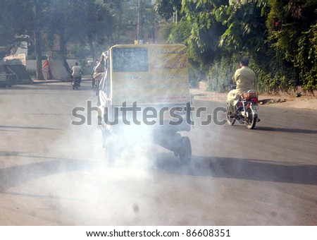 LAHORE, PAKISTAN - OCT 13: Auto-rickshaw emits smoke passes through a road violates traffic laws showing the negligence of traffic police department on October 13, 2011in Lahore, Pakistan.