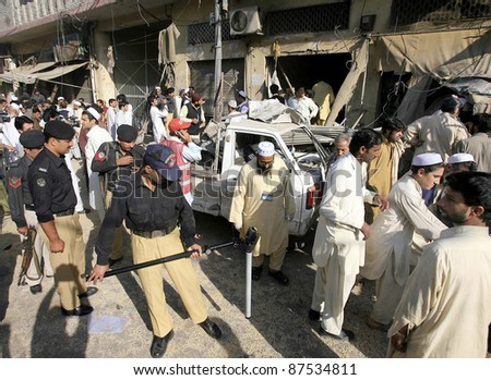 PESHAWAR, PAKISTAN - OCT 27: People gather near damaged vehicle and shops which were destroyed in explosion after explosion at Rampura Bazaar in Peshawar on Thursday, October 27, 2011.