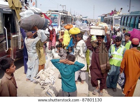 HYDERABAD, PAKISTAN - OCT 31: People, who were displaced and affected by recent rain and flood, with their belongs near buses as they are going back to their areas on October 31, 2011 in Hyderabad, Pakistan.