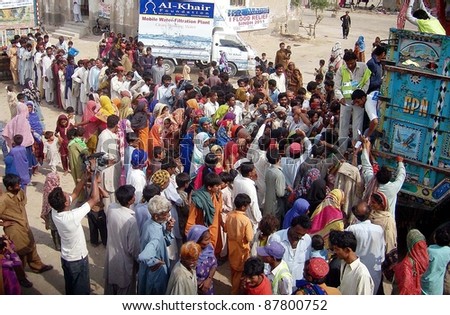 HYDERABAD, PAKISTAN - OCT 31: People, who were displaced and affected by recent rain and flood, gather to get food while volunteers distribute food of one month on October 31, 2011 in Hyderabad. Pakistan.