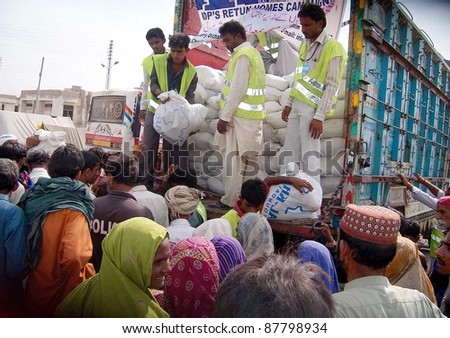 HYDERABAD, PAKISTAN - OCT 31: People, who were displaced and affected by recent rain and flood, gather to get food while volunteers distribute food of one month on October 31, 2011 in Hyderabad Pakistan.