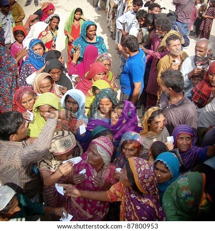 HYDERABAD, PAKISTAN - OCT 31: People, who were displaced and affected by recent rain and flood, gather to get food while volunteers distribute food of one month on October 31, 2011 in Hyderabad Pakistan.