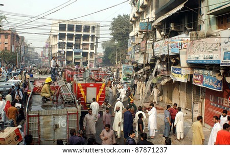 LAHORE, PAKISTAN - NOV 01: Firefighters busy in rescue operation while people gather after fire broke out at electronics market located at Hall Road on November 01, 2011 in Lahore, Pakistan.