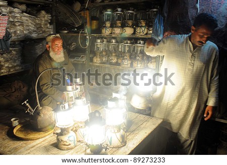 KARACHI, PAKISTAN - NOV 21: A shopkeeper carries lantern on rent for his shop during electricity load-shedding in a main commercial market of city on November 21, 2011in Karachi.