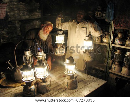 KARACHI, PAKISTAN - NOV 21: A shopkeeper carries lanterns on rent for his shop during electricity load-shedding in a main commercial market of city in Karachi on Monday, November 21, 2011.