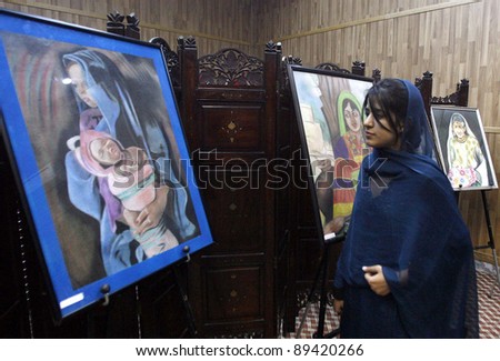PESHAWAR, PAKISTAN - NOV 23: A student takes keen interest paintings during an exhibition arranged by Khana Farhang Iran held on  November 23, 2011in Peshawar.