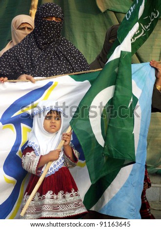 KARACHI, PAKISTAN - DEC 20: A child supporter of Jamat-e-Islami (JI) Women Wing holds National flag during Tahafuz-e-Pakistan Khawateen rally in Karachi, Pakistan on December 20, 2011.