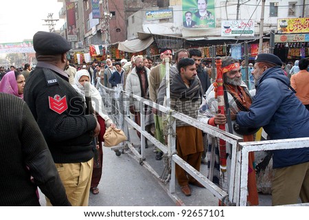 LAHORE, PAKISTAN - JAN 13: A policeman takes body search of people who are entering in Data Darbar as security has been tightened on occasion of the Urs celebrations on January 13, 2012 in Lahore, Pakistan.