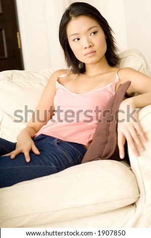 A pretty asian woman sitting on a beige sofa (shallow depth of field used)