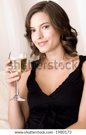 A young woman relaxes at home on the sofa with a glass of white wine (shallow depth of field used)