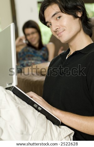 A young couple relaxing at home with the man working on a laptop computer (shallow depth of field used)