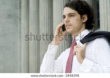 A young businessman making a phone call in front of an old building (shallow depth of field used)