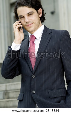 A young businessman making a call on mobile phone outside