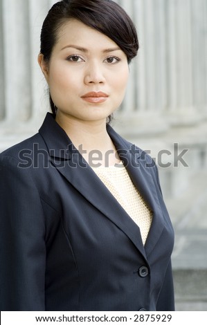 A young businesswoman wearing business suit standing in front of an old building (shallow depth of field)
