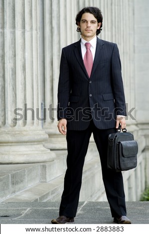 A young businessman standing holding a briefcase bag