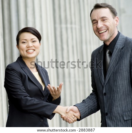 Two business people smiling and shaking hands