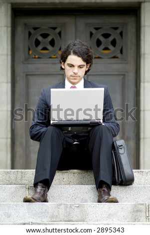 A young businessman using a laptop outside