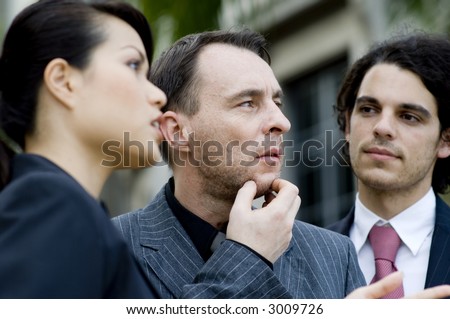 Three business people outside with the middle person thinking and in focus