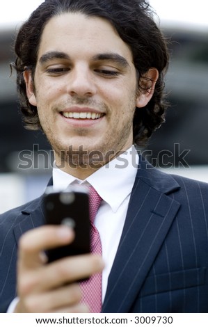 A young businessman outside using a phone to send text message