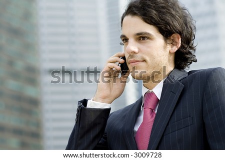 A young businessman in the city using a mobile phone outside (shallow depth of field used)