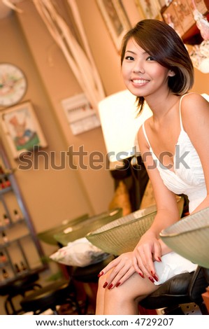 A young attractive asian woman sitting in a cosy beauty salon (shallow depth of field used)
