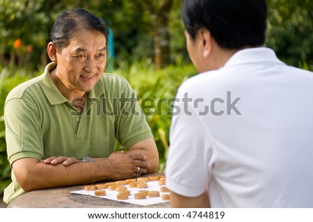 Two Chinese men in their fifties playing chess in the park
