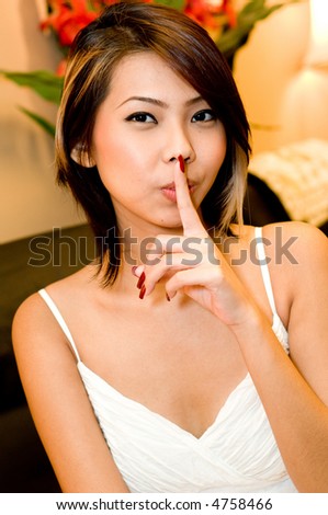 A young attractive Asian woman with her finger on her lips