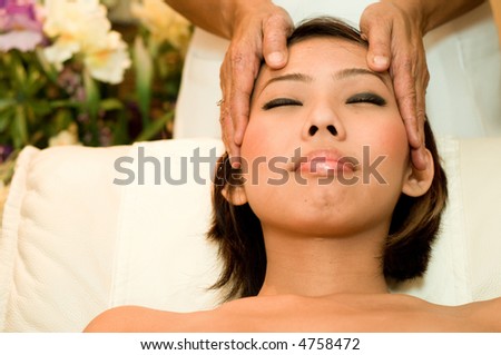 A young Asian woman having her head massaged in a salon
