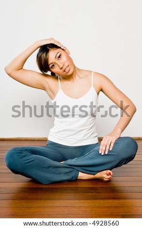 A pretty young Asian woman stretching in a studio