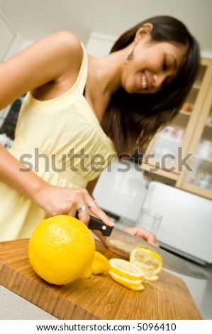 A beautiful young Asian woman slicing lemons in the kitchen