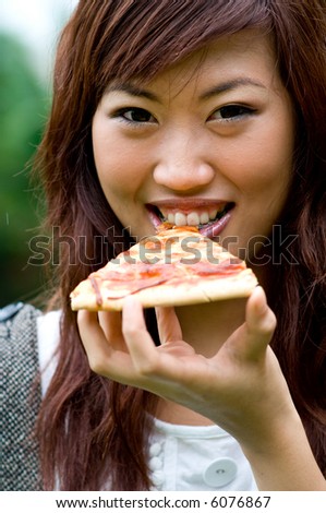 Young attractive asian women eating a slice of pizza