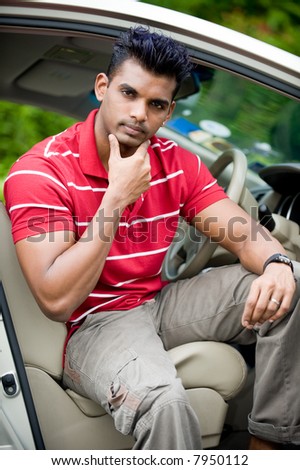A well-built Asian man in a saloon car in the country