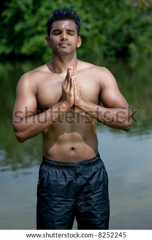 A well-built young man practicing yoga outdoors
