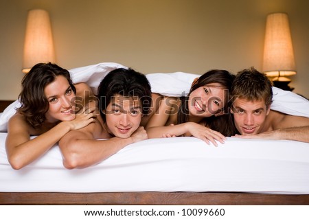 Four friends all lying together in a double bed
