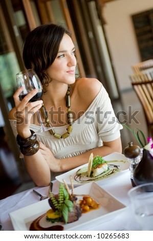 A young woman enjoying a meal and wine