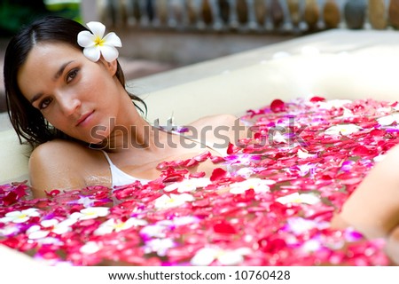 A young woman in a bath full of flowers