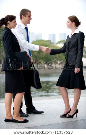 Three business executives meeting and greeting by a river in the City