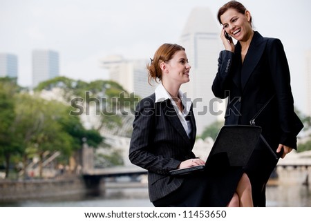 Two young attractive businesswoman working outside by Singapore river