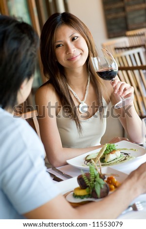 A young woman smiling whilst eating dinner at a restaurant