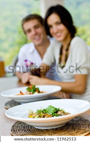 A young couple on vacation eating lunch at a relaxed outdoor restaurant (focus on food)