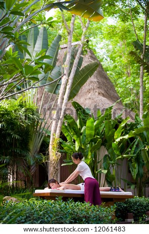 A young woman having massage outside in tropical garden