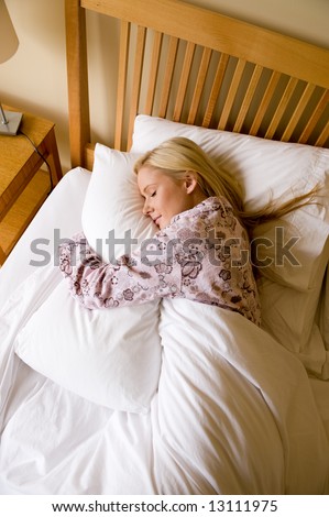 A young woman in pyjamas asleep in bed