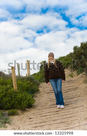 A young attractive woman walking along a sandy path in autumn