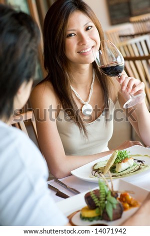 A young woman smiling whilst eating dinner at a restaurant