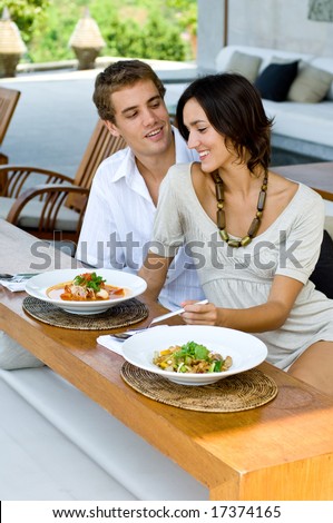 A young couple on vacation eating lunch at a relaxed outdoor restaurant